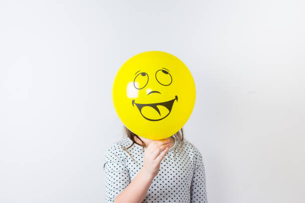 joven linda chica sosteniendo baloon sobre fondo blanco. día de los tontos de abril. sonrisa baloon - fool fotografías e imágenes de stock