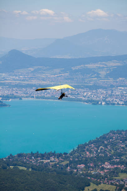 istock Hang-glider Instructor Flying in Hang-glider with Customer over Annecy Lake Through Mountain Landscape and Cities 1128916411
