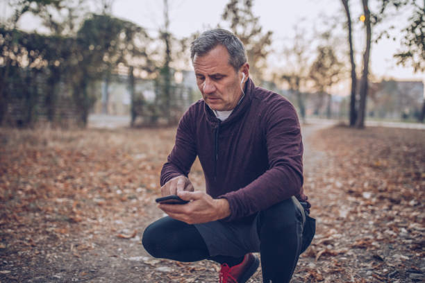 istock Senior man using phone after jogging at the park 1128917257