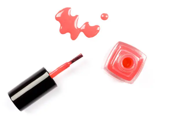 Poured coral nail polish with a bottle isolated on white background.