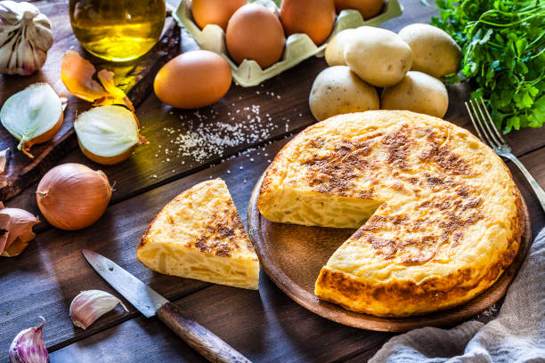 kuchnia hiszpańska: hiszpańska tortilla ze składnikami na drewnianym stole kuchennym - omelet breakfast eggs onion zdjęcia i obrazy z banku zdjęć