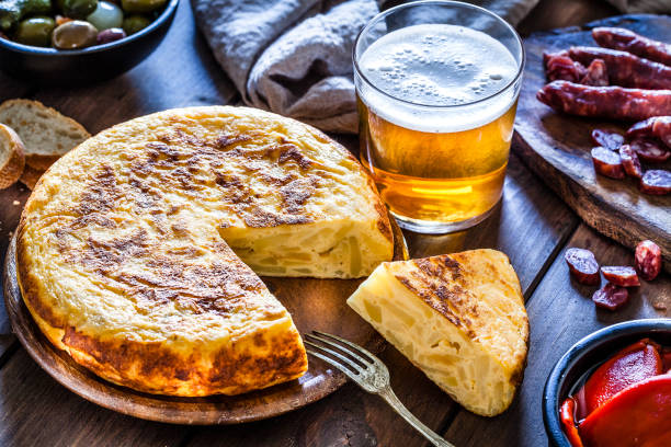 tapas: tortilla española, chorizo, pimientos, aceitunas y cerveza filmada desde arriba - spanish cuisine fotografías e imágenes de stock