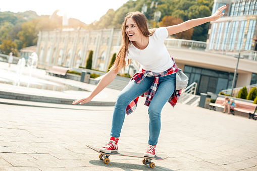 Young female with skateboard outdoors active smiling