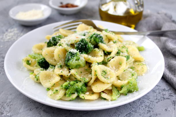 Homemade pasta orecchiette with broccoli, Parmesan cheese and chili pepper on light background. stock photo