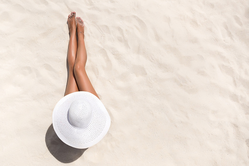 Concepto de moda de vacaciones de verano - bronceado mujer usa sombrero para el sol en la playa de arena blanca y un tiro desde arriba photo
