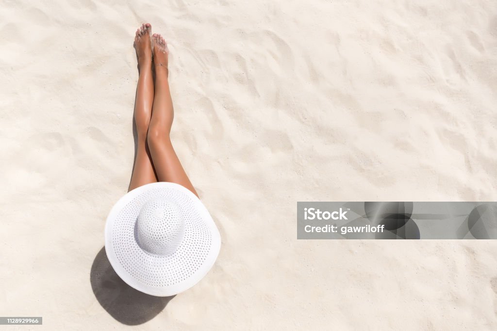 Concepto de moda de vacaciones de verano - bronceado mujer usa sombrero para el sol en la playa de arena blanca y un tiro desde arriba - Foto de stock de Mujeres libre de derechos