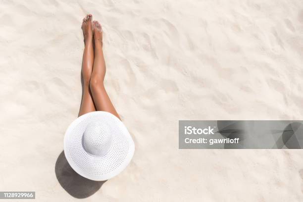 Summer Holiday Fashion Concept Tanning Woman Wearing Sun Hat At The Beach On A White Sand Shot From Above Stock Photo - Download Image Now