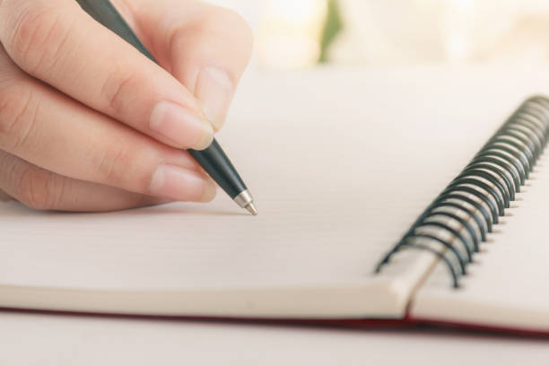 istock Woman hand with pen writing on notebook. Blank copy space. 1128931216
