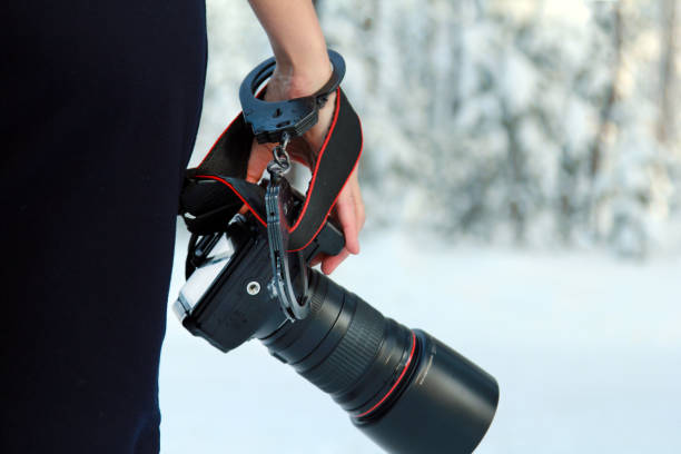 istock Girl with a camera in hand. Fastened with handcuffs. 1128931529