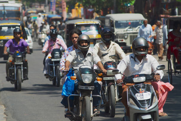 People ride motorbikes by the street during morning rush hour in Jaipur, India. Jaipur, India - March 30, 2007: Unidentified people ride motorbikes by the street during morning rush hour in Jaipur, India. india jaipur rajasthan traditional culture stock pictures, royalty-free photos & images