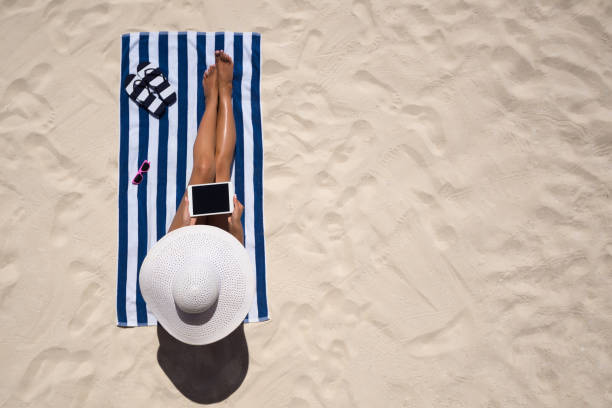 concept de mode de vacances d’été - portant chapeau femme sur la plage sur un sable blanc tiré de dessus de bronzage - deck chair photos et images de collection