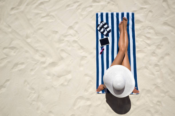 concept de mode de vacances d’été - portant chapeau femme sur la plage sur un sable blanc tiré de dessus de bronzage - deck chair photos et images de collection