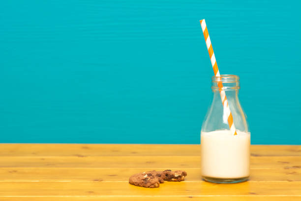 straw and half full milk bottle with a half-eaten cookie - milk milk bottle drinking straw cookie imagens e fotografias de stock