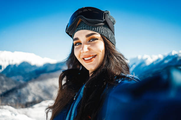 istock Attractive snowboard girl smiling and making selfie on mountain background. 1128933203