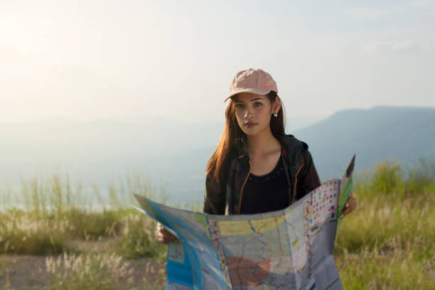 istock Portrait Of Smiling Woman Holding Map While Standing On Field 1128935441