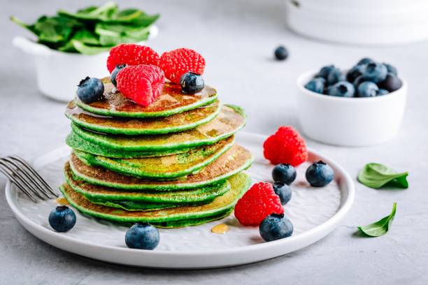 istock Healthy green spinach pancakes with raspberries, blueberries and honey 1128935557