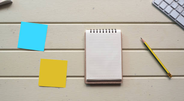 istock Working space, notebook with post it and keyboard  on white wooden desk 1128938987