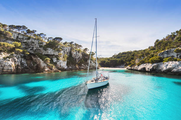 Sailboat in beautiful lagoon, Menorca island Beautiful beach with sailing boat, Menorca island, Spain bay of water stock pictures, royalty-free photos & images