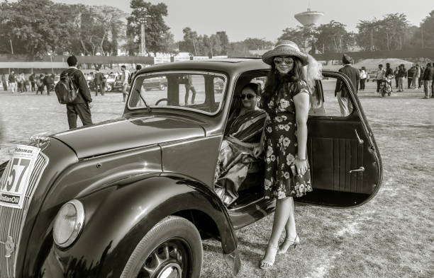 February 03,2019. Black and White Image of A Beautiful Young Indian girl wearing western dress poses with an Austin Vintage car at Statesman Vintage and Classic Car rally at Kolkata, India.