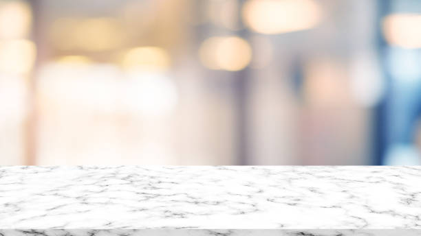 blurred lamp light at shopping mall background with modern white marble tabletop for show,promote and advertise product on display , luxury interior design template concept