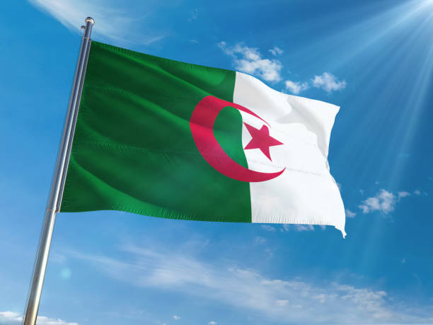 istock Algeria National Flag Waving on pole against sunny blue sky background. High Definition 1128948457