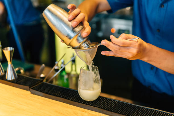 istock Mixologist making cocktail with Shaker, Double Size Jiggers and drinking glass with ice cube on cocktail counter bar. 1128948487
