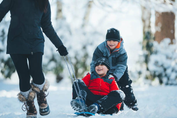 istock Mom pulls her son through the snow on a sled 1128948615