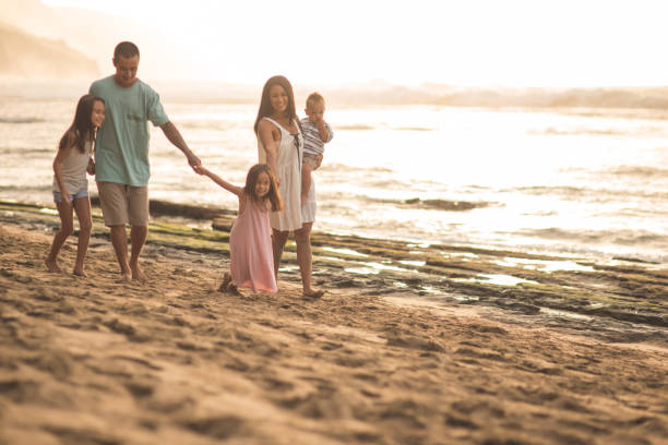 eurasische mama und papa spaziergang am strand mit ihren drei kindern - eurasian ethnicity stock-fotos und bilder