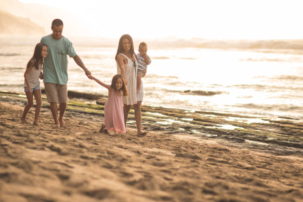 pai e mãe da eurásia andar pela praia com seus três filhos - beach park - fotografias e filmes do acervo