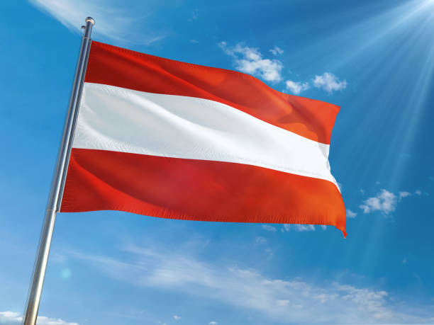 istock Austria National Flag Waving on pole against sunny blue sky background. High Definition 1128950238