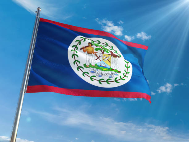 istock Belize National Flag Waving on pole against sunny blue sky background. High Definition 1128951060