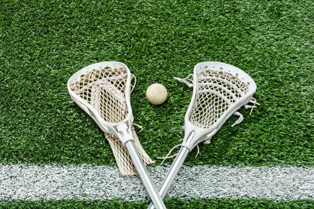 Looking down on a pair of Lacrosse sticks and a ball on the midfield-line stock photo