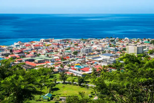 Bright and colorful image of Roseau with buildings along the coastline and at the cruise port of Dominica. Ocean and blue sky background. View from a hill.