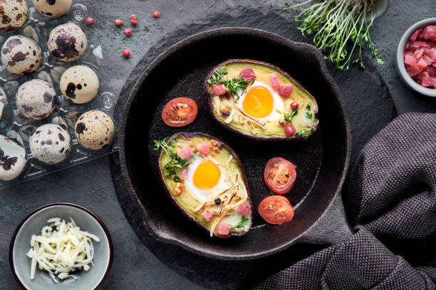 istock Keto diet dish: Avocado boats with ham cubes, quail eggs, cheese, ingredients around 1128956270
