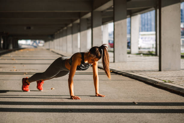 istock Young woman doing push ups in the urban environment 1128956325