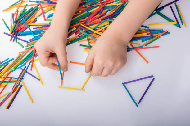 istock Kid making geometric shapes with colorful sticks on white background 1128956805