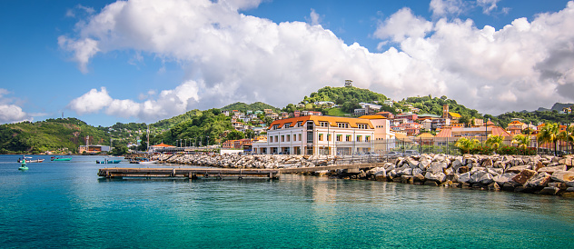 Beautiful horizontal image of St George's, cruise port in Grenada. Blue sky with white clouds, waterfront and bright buildings along the coastline.