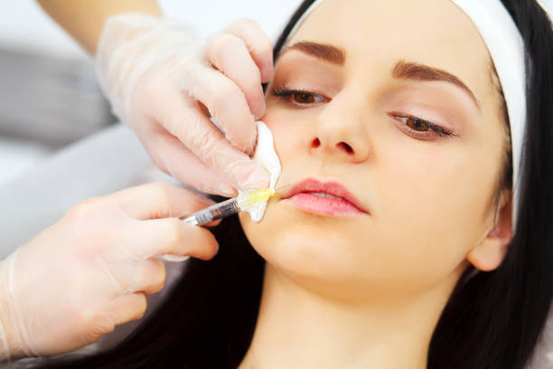istock beautician doing beauty injection to woman lips 1128959852