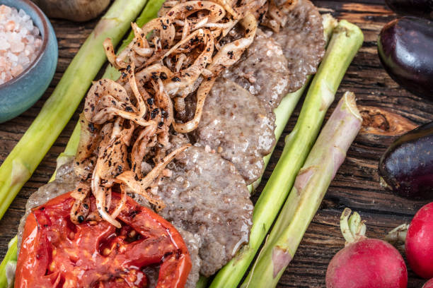 istock Turkish meatballs, (Turkish Food Kofte or Kofta), created background with vegetables, Meatballs on asparagus. 1128960021