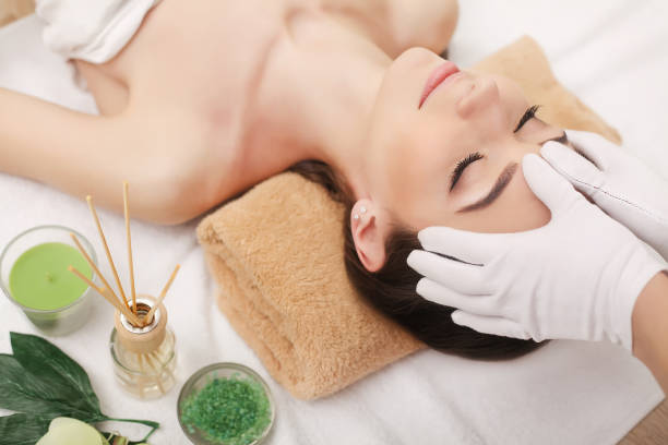 istock Young pretty woman enjoying face massage procedure 1128961456