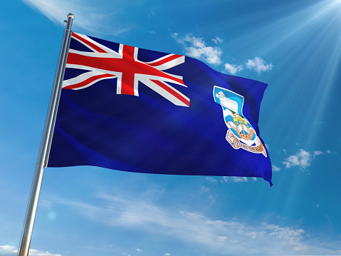 Falkland Islands National Flag Waving on pole against sunny blue sky background. High Definition