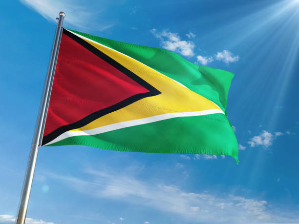 istock Guyana National Flag Waving on pole against sunny blue sky background. High Definition 1128964556