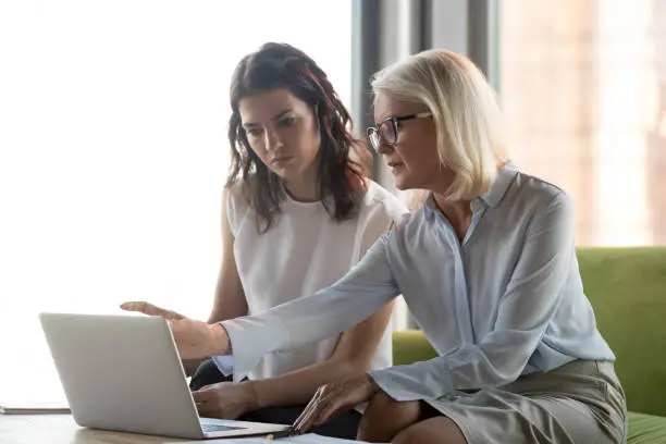 Photo of Serious middle aged executive manager explaining colleague online work