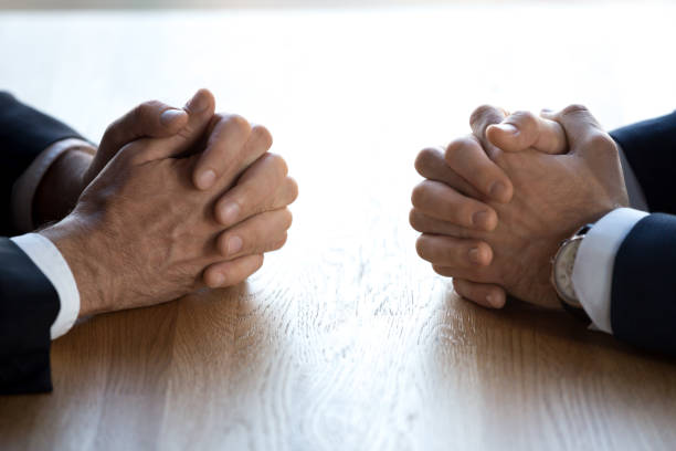 istock Clasped hands of two businessmen negotiators opponents opposite on table 1128967650