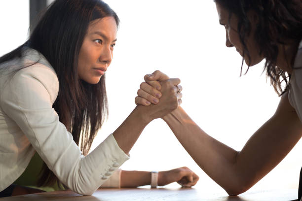 lucha para el armrestling de jóvenes empresarias asiáticas y caucásicas para liderazgo - conflict competition arm wrestling business fotografías e imágenes de stock