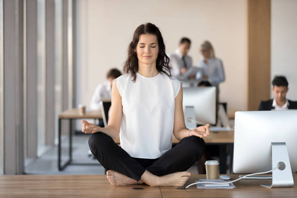 仕事机でヨガを行使して穏やかな若い実業家 - zen like meditating yoga business ストックフォトと画像