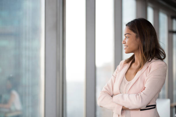 istock Smiling confident african businesswoman looking at window thinking about future 1128967679