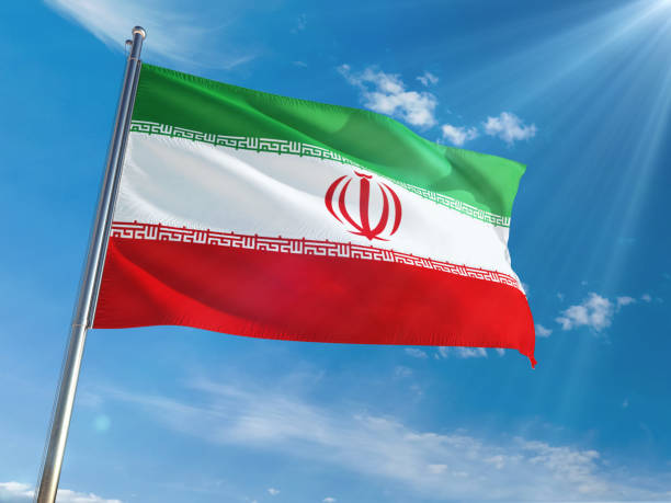 istock Iran National Flag Waving on pole against sunny blue sky background. High Definition 1128969017