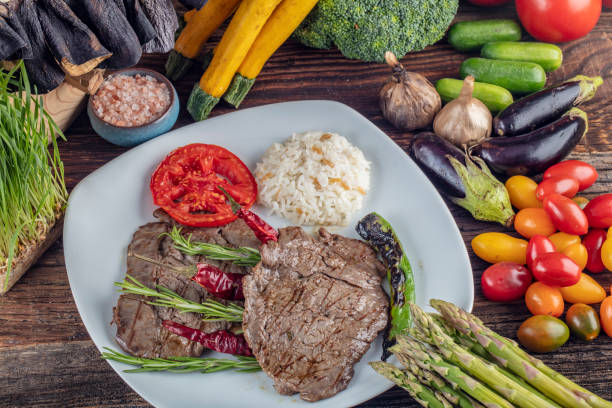 istock Medium rare beef tenderloin grilled, created background with vegetables on wooden background. 1128969064