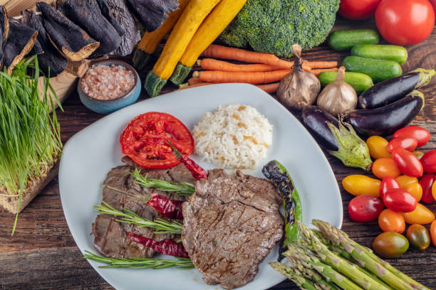 istock Medium rare beef tenderloin grilled, created background with vegetables on wooden background. 1128969522